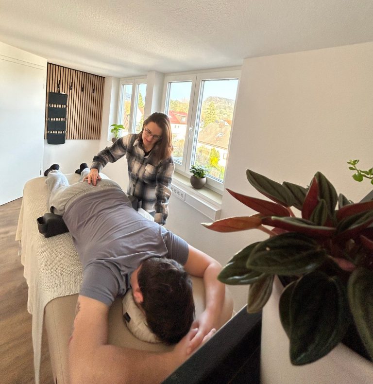 Eine Person erhält von Franziska eine Spinalflow Einheit in einem ruhigen Raum. Die Person liegt dabei auf einer hellen Spinalflow Liege.
