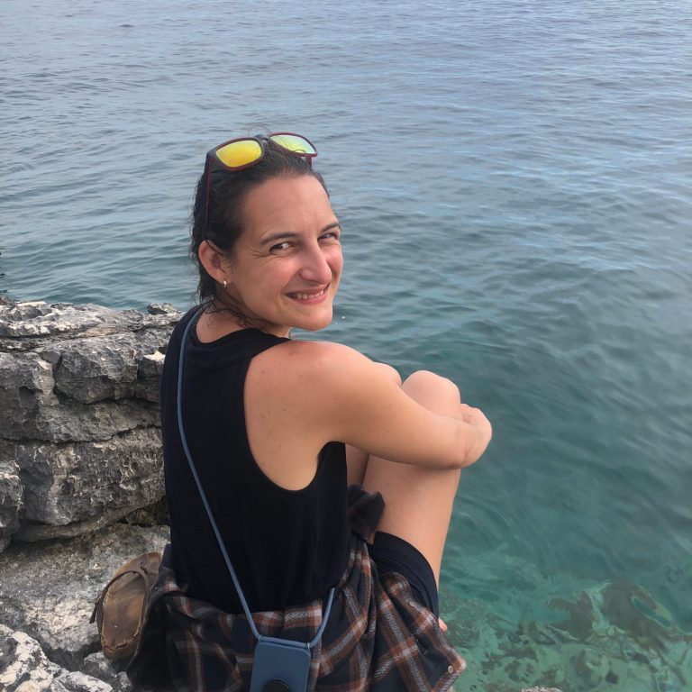 Franziska sitzt auf Felsen am Ufer des Meeres und blickt lachend über ihre rechte Schulter in die Kamera. Franziska sitzt auf Felsen am Ufer des Meeres und blickt lachend über ihre rechte Schulter in die Kamera.
