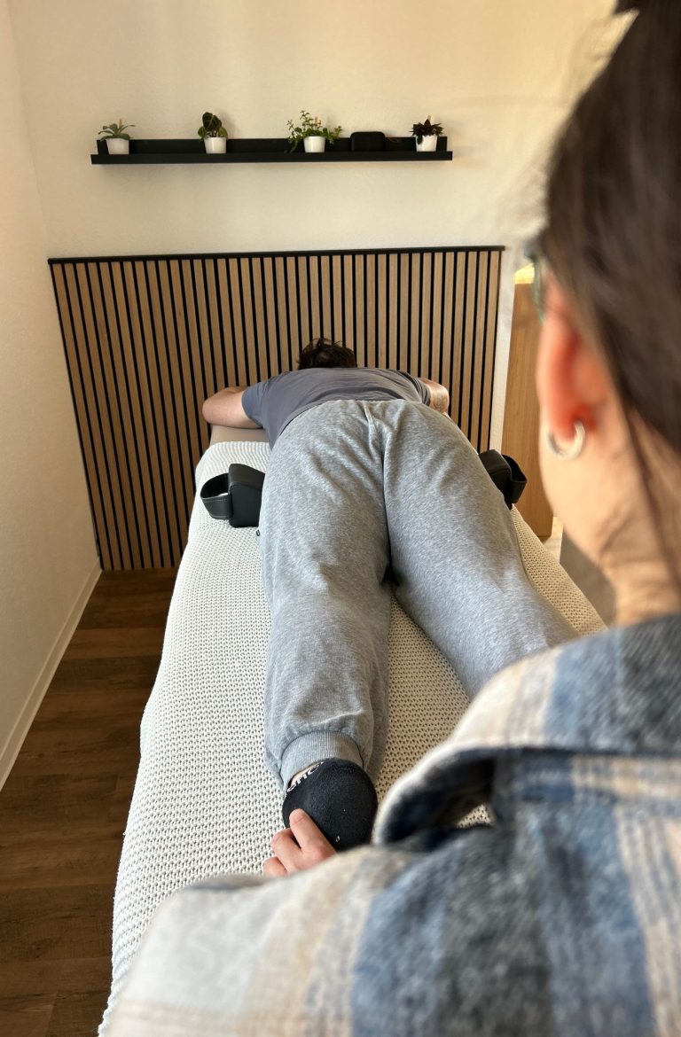 Person liegt auf dem Bauch auf der liege und Franziska steigert den Wirbelsäulenfluss durch Berührung dr Füße. Person liegt auf dem Bauch auf der liege und Franziska steigert den Wirbelsäulenfluss durch Berührung der Füße.